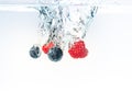 BlueberryÃ¢â¬â¢s and raspberries splashing into crystal clear water with air bubbles Royalty Free Stock Photo